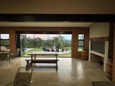 a living room with a table and a large window at Elements Golfers Lodge 123 in Moheme