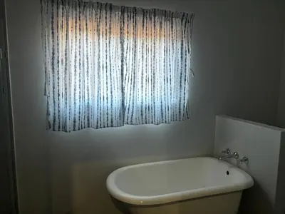 a bathroom with a white toilet and a window at Elements Golfers Lodge 123 in Moheme
