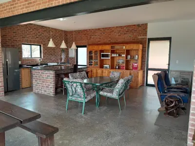 a kitchen with a table and chairs and a brick wall at Elements Golfers Lodge 123 in Moheme