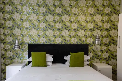 a bedroom with a large bed with green pillows at Touch of Class Guest House in Pretoria