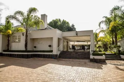 a white house with palm trees and a driveway at Touch of Class Guest House in Pretoria