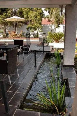 a patio with a pond with a table and chairs at Touch of Class Guest House in Pretoria
