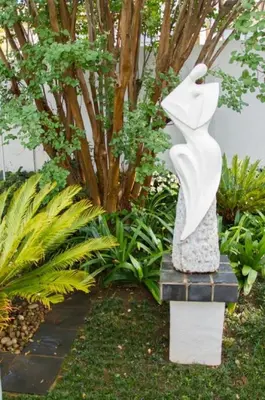 a statue of a woman sitting in a garden at Touch of Class Guest House in Pretoria