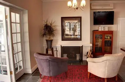a living room with two chairs and a fireplace at Touch of Class Guest House in Pretoria
