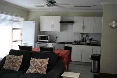 a living room with a couch and a kitchen at Touch of Class Guest House in Pretoria