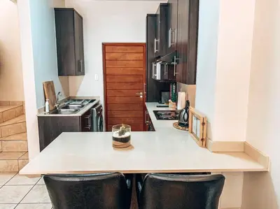 a kitchen with a counter and two stools at a kitchen island at Luxury Duplex in Pretoria East in Pretoria