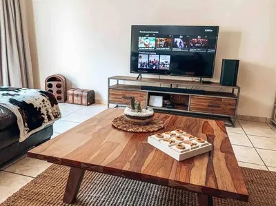a living room with a coffee table and a flat screen tv at Luxury Duplex in Pretoria East in Pretoria
