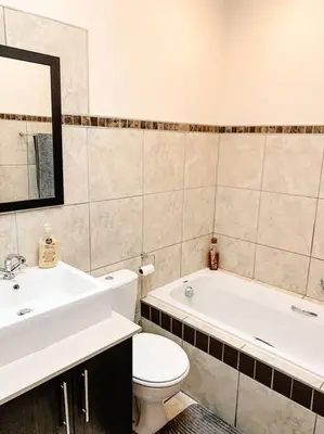 a bathroom with a sink and a toilet and a tub at Luxury Duplex in Pretoria East in Pretoria