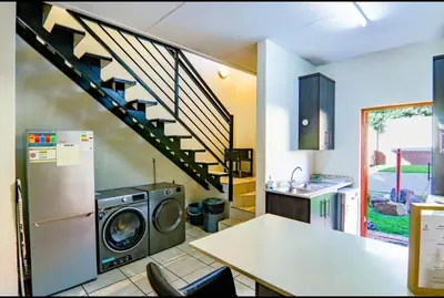 a kitchen with a washing machine and a staircase at Luxury Duplex in Pretoria East in Pretoria