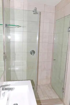a shower with a glass door next to a sink at The Thorn by the airport in Kempton Park