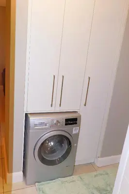 a washing machine in a room with white cabinets at The Thorn by the airport in Kempton Park