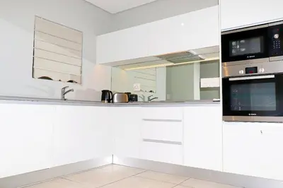 a white kitchen with white cabinets and appliances at The Thorn by the airport in Kempton Park