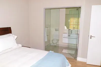a bedroom with a bed and a bathroom with a toilet at The Thorn by the airport in Kempton Park