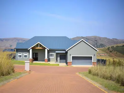 a house with a garage and mountains in the background at Highland Peace Haven In Dullstroom in Dullstroom