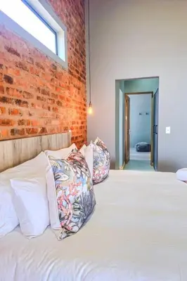 a bedroom with a brick wall and a bed with pillows at Highland Peace Haven In Dullstroom in Dullstroom