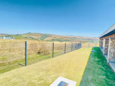 a fence next to a field with a building at Highland Peace Haven In Dullstroom in Dullstroom