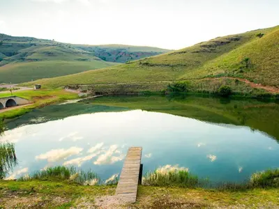 a pond in a field with clouds in the water at Highland Peace Haven In Dullstroom in Dullstroom