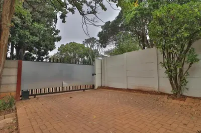 a white fence with a brick sidewalk and trees at Crowley Cottage in White River
