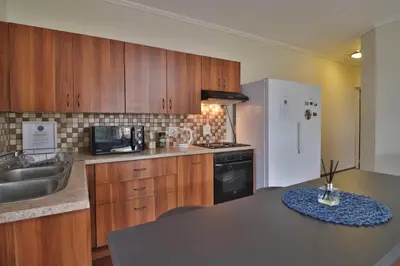 a kitchen with wooden cabinets and a sink and a refrigerator at Crowley Cottage in White River