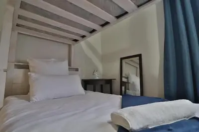 a bedroom with a white bed and a mirror at Crowley Cottage in White River