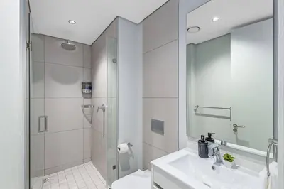 a white bathroom with a shower and a sink at 2 Bed Luxury Apartment, Ellipse, Waterfall in Midrand