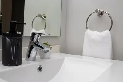 a bathroom sink with a faucet and a towel at 2 Bed Luxury Apartment, Ellipse, Waterfall in Midrand