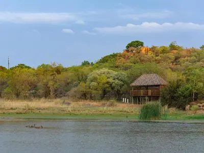 a hut next to a body of water at Dikhololo in Brits