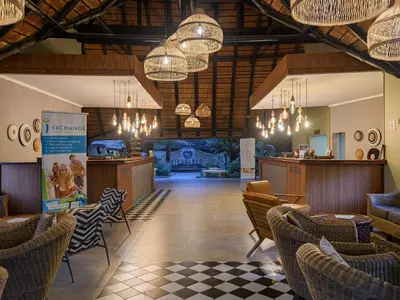 a lobby of a restaurant with chairs and chandeliers at Dikhololo in Brits