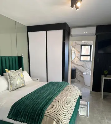 a bedroom with a large bed and a bathroom at Kingdoms Lodge in Groblersdal