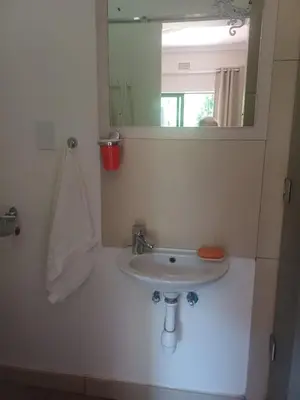 a bathroom with a sink and a mirror at Countrylane Lodge in Midrand