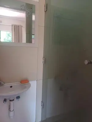 a bathroom with a sink and a mirror at Countrylane Lodge in Midrand