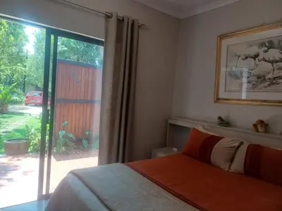 a bedroom with a bed and a large window at Countrylane Lodge in Midrand