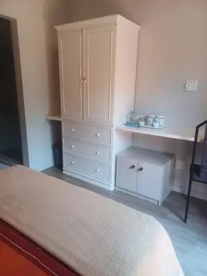 a bedroom with a white cabinet and a desk at Countrylane Lodge in Midrand