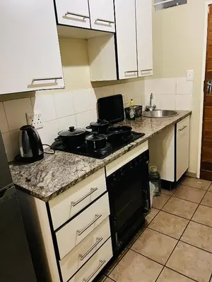 a kitchen with white cabinets and a stove top oven at Mbizo Cozy Retreat 307 in Pretoria