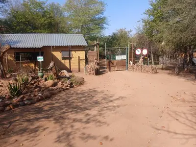 a building with a gate next to a dirt road at Mbaula lodge in Letaba Wildlife Reserve