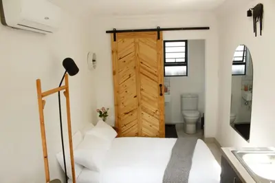 a bedroom with a white bed and a wooden door at Cozy Box Haus in Graskop