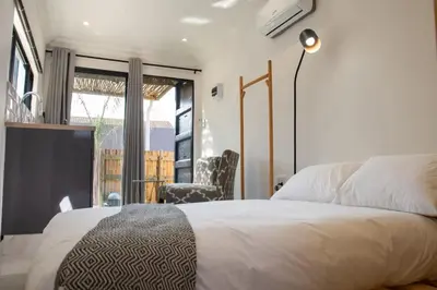 a bedroom with a bed and a chair and a window at Cozy Box Haus in Graskop