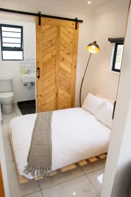 a bedroom with a bed and a wooden door at Cozy Box Haus in Graskop