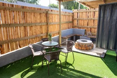 a patio with a table and chairs and a fence at Cozy Box Haus in Graskop