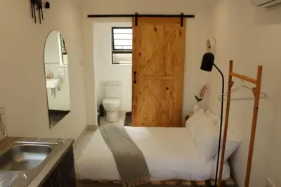 a bathroom with a bed with a wooden door and a sink at Cozy Box Haus in Graskop
