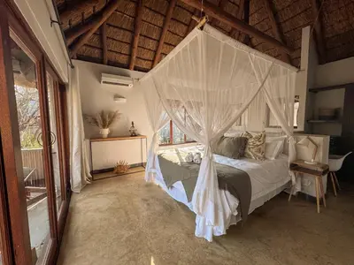 a bedroom with a bed with a mosquito net at Raptors Lodge - NXALATI in Hoedspruit