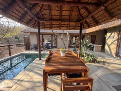 a wooden table on a deck next to a pool at Raptors Lodge - NXALATI in Hoedspruit