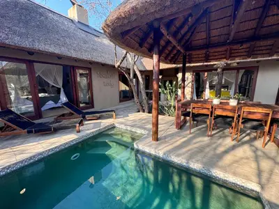 a house with a swimming pool and a table and chairs at Raptors Lodge - NXALATI in Hoedspruit