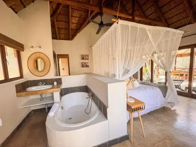 a bedroom with a tub and a bed and a sink at Raptors Lodge - NXALATI in Hoedspruit
