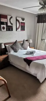 a bedroom with a large white bed with pictures on the wall at Malikana Guesthouse in Kempton Park