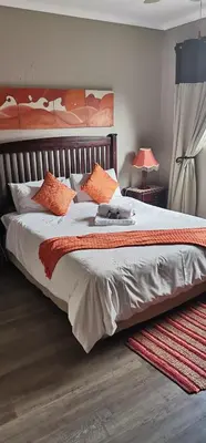 a bedroom with a large bed with orange pillows at Malikana Guesthouse in Kempton Park