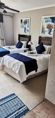 a bedroom with two beds with blue pillows at Malikana Guesthouse in Kempton Park