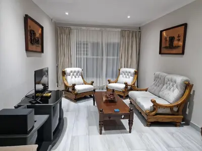 a living room with a couch and chairs and a tv at Amen guest apartment in Pretoria