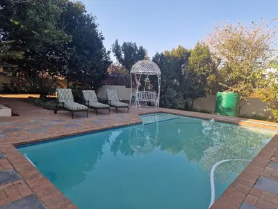 a swimming pool with two chairs and a gazebo at Amen guest apartment in Pretoria