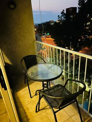 a glass table and two chairs on a balcony at Mbizo Cozy Retreat 409 in Pretoria